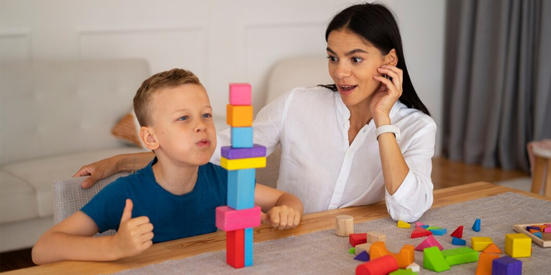 Child building a colorful block tower with a caregiver, illustrating early intervention activities that support development and learning for children with disabilities.
